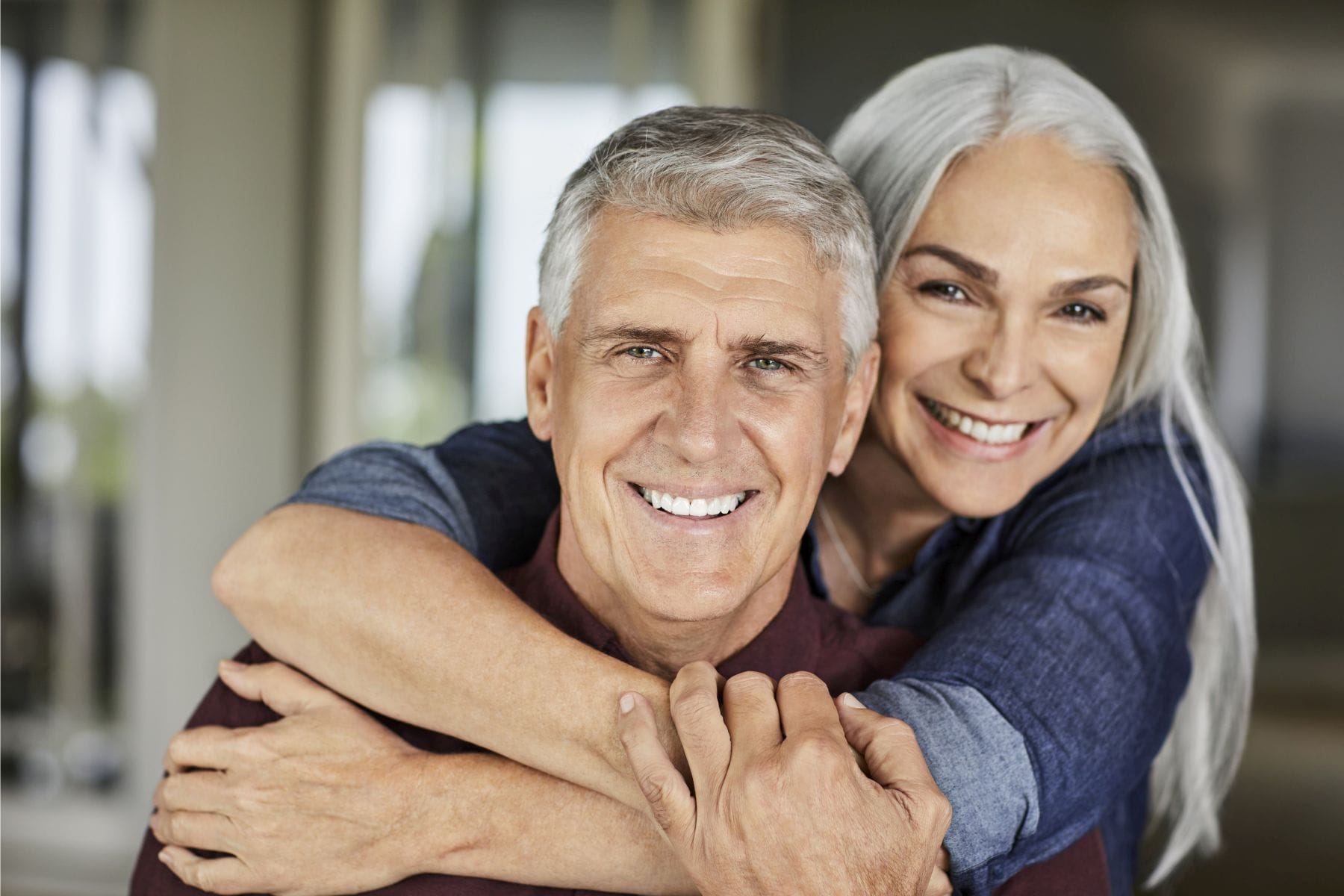 Portrait of happy mature man and woman. Heterosexual couple is spending leisure time at home during COVID-19 lockdown. They are wearing casuals.